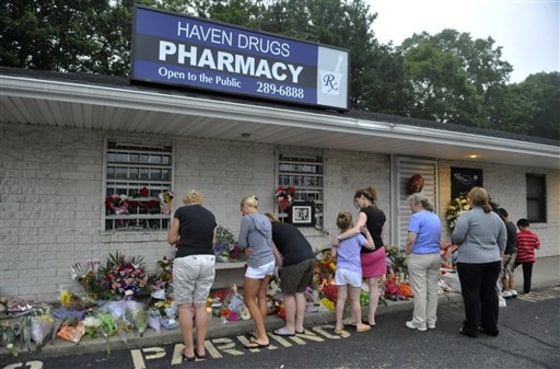 People bring flowers to Haven Drugs pharmacy where four people were killed during a botched weekend painkiller robbery in Medford, N.Y.